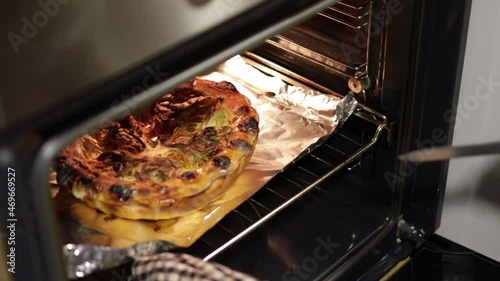 Hand opening oven door and checking pumpkin with a knife. Traditional autumn food