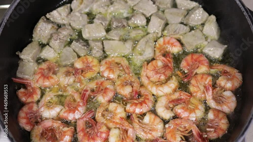 Shrimps and tuna in a frying pan on a gas stove