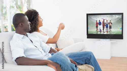 Rear view of african american couple sitting at home together watching sport event on tv