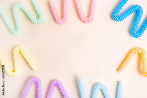 Trendy kids toys pastel colorful pop-tube on beige background. Set of forms and colors corrugated pipe and anti stressing, relaxation fidget finger toys. 