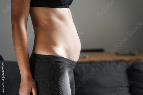 Young woman side view of body. Swollen belly. Pregnancy. Diastasis recti after child birth. Fitness exercises and diet for weight loss.  photo