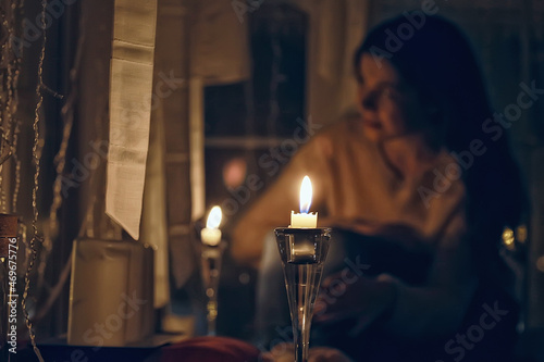 girl at the window dreams in winter evening / the romance of candle, the beautiful model in Christmas evening dreams