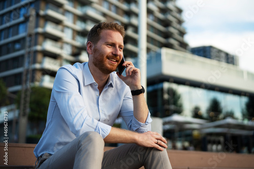 Businessman using the phone while sitting on the stairs. Happy man using the phone