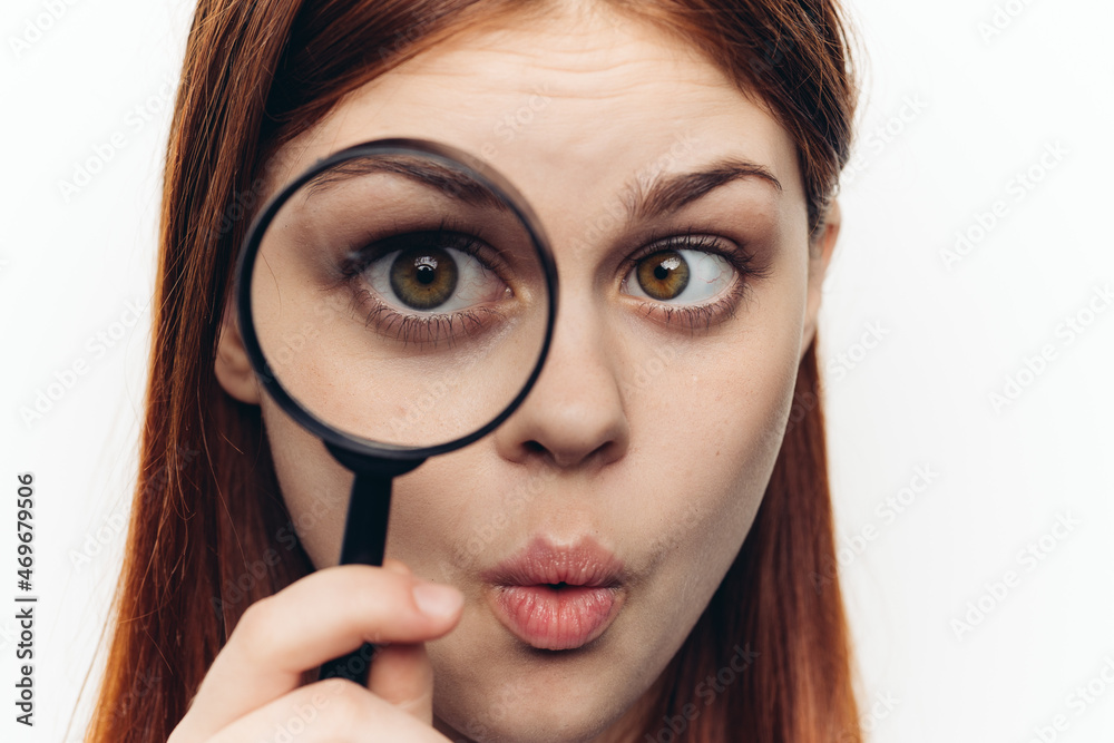 pretty woman grimacing with magnifying glass near face close-up pretty woman grimacing with magnifying glass near face close-up