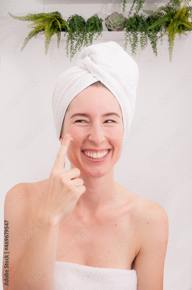 Laughing girl applying moisturizing cream on her face. Skin care and beauty concept Laughing girl applying moisturizing cream on her face. Skin care and beauty concept