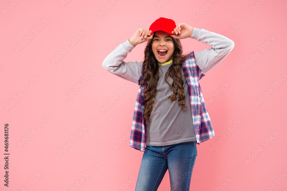 happy laughing teen girl hipster in cap on pink background with copy space, fashionista