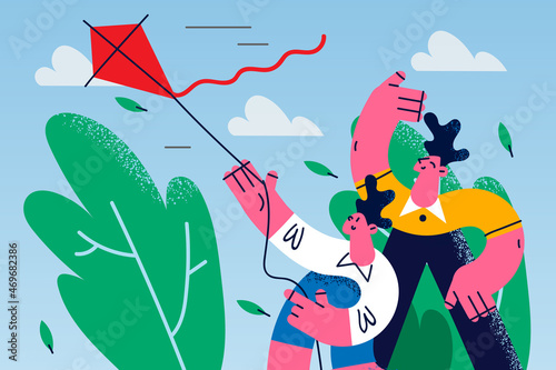 Smiling dad and child play with paper kite