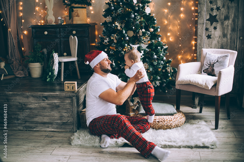 Obraz premium Smiling man holding his baby while playing near Christmas tree