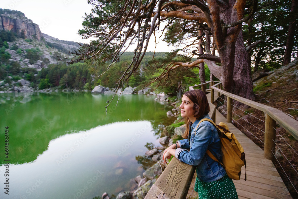 Panoramic view of caucasian woman sightseeing on pathway isolated with backpack. Horizontal view of woman traveling alone in the black lagoon in Soria. People and travel destinations in Spain.