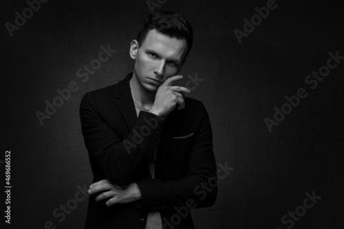 Black and white portrait of a handsome business man in a suit against a dark background.