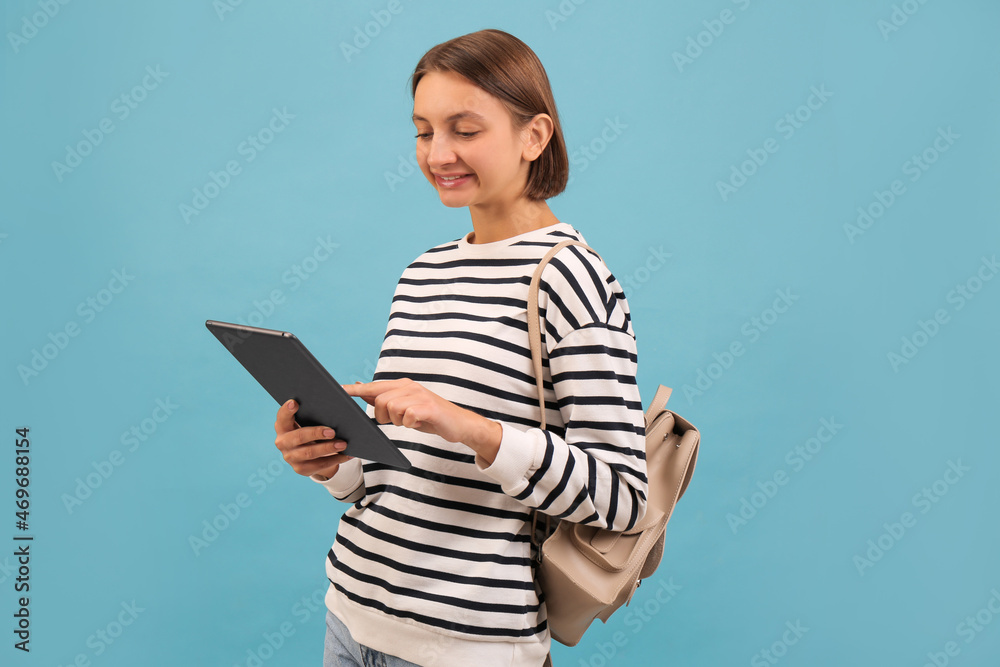 Young student with backpack and tablet on light blue background Young student with backpack and tablet on light blue background