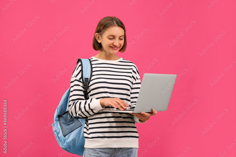 Young student with laptop and backpack on pink background Young student with laptop and backpack on pink background