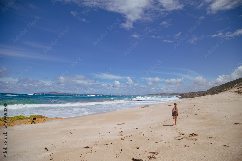 Girl walking on beach under clear blue sky at Portland Victoria Australia