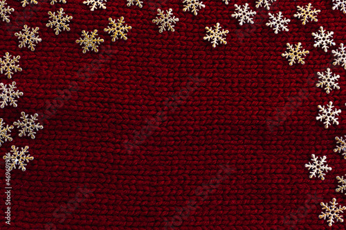 Golden snowflakes on red knitted background. Winter holidays concept. Snow winter fantasy. Christmas décor. Christmas greeting card or New Year card. Top view. Flat lay. Place for text. Copy space.