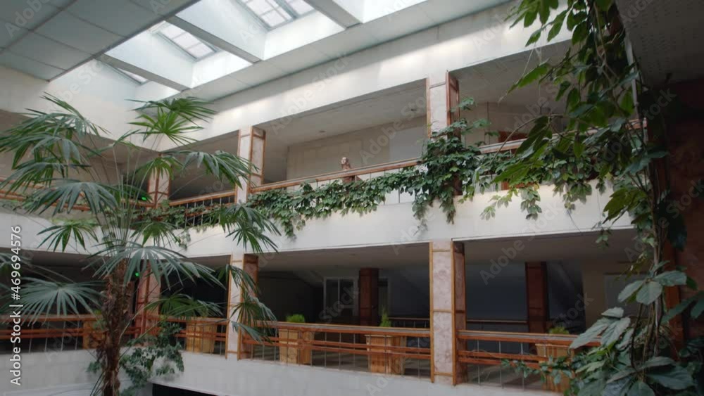 Young tender woman is dancing alone near balustrade in big beautiful lobby, decorated with huge plants, talented dancer in isolation, Zoom in, Slow motion. Young tender woman is dancing alone near balustrade in big beautiful lobby, decorated with huge plants, talented dancer in isolation, Zoom in, Slow motion.