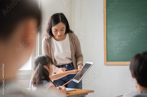 Asian Beautiful female teacher teaching Asian girl learning with digital tablet in classroom