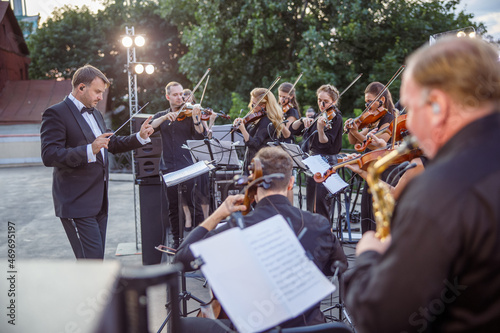 Conductor directing orchestra performance on outdoor stage