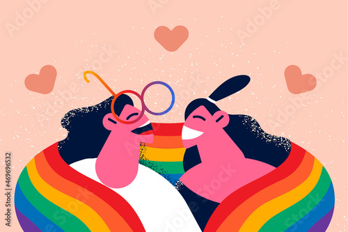 Happy lesbian couple covered in LGBT flag 