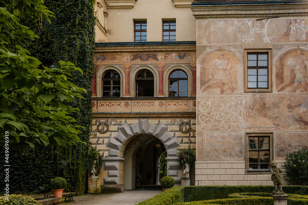 Castolovice, Eastern Bohemia, Czech Republic, 11 September 2021: renaissance castle with tower at sunny day, courtyard with arcades and geometric flower beds, murals and sgraffito plaster on walls