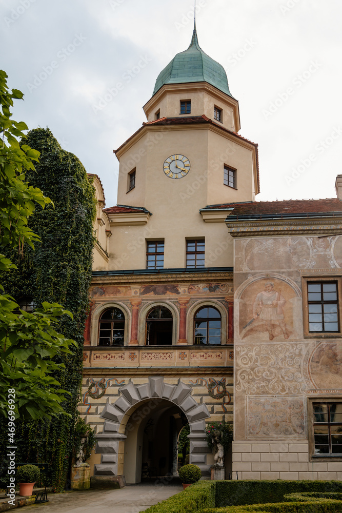 Castolovice, Eastern Bohemia, Czech Republic, 11 September 2021: renaissance castle with tower at sunny day, courtyard with arcades and geometric flower beds, murals and sgraffito plaster on walls