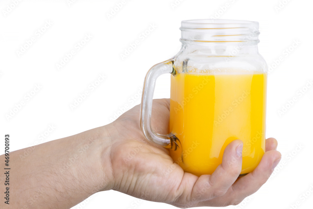 A hand holding a jar of orange juice isolated on a white background.Orange juice in a glass . A hand holding a jar of orange juice isolated on a white background.Orange juice in a glass .