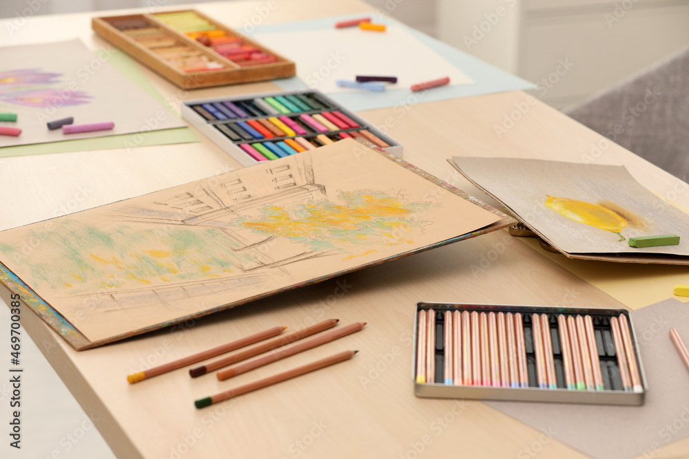 Artist's workplace with drawings, soft pastels and color pencils on table Artist's workplace with drawings, soft pastels and color pencils on table