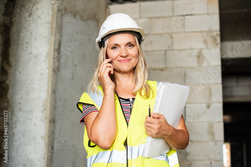 Female foreman officer inspector, building Inspector, engineer or inspector at construction site checking and inspecting progressing work in construction site, in hardhat and high-visibility vest photo