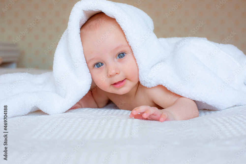 baby boy after bathing wrapped in a white towel, lying in the bedroom on the bed at home baby boy after bathing wrapped in a white towel, lying in the bedroom on the bed at home