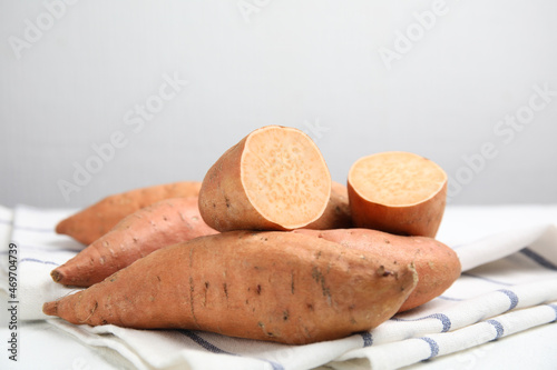 Whole and cut ripe sweet potatoes on kitchen towel