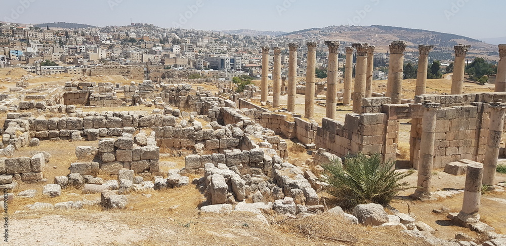 Le célèbre site touristique jordanien - Jerash, avec ses constructions ou de grandes colonnes de marbres, sans toit, grande zone de vestige historique et de style romain, plaine d'herbes secs