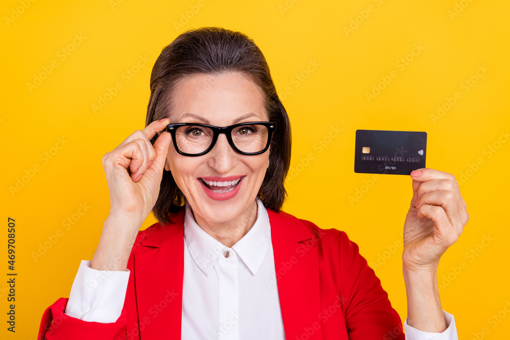 Photo of funky aged brunette lady hold card wear spectacles red cardigan isolated on yellow color background Photo of funky aged brunette lady hold card wear spectacles red cardigan isolated on yellow color background