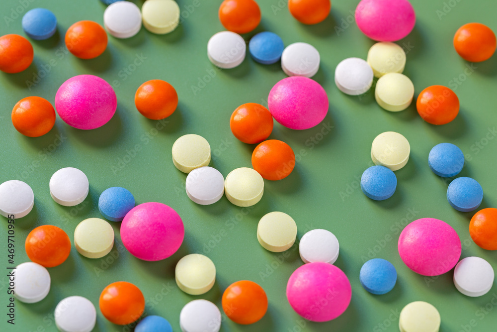 Tablets and vitamins of different shapes and colors on a green background. Medical education Tablets and vitamins of different shapes and colors on a green background. Medical education