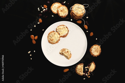 Plate of oatmeal, cranberry and almond cookies on dark background. Flat lay.