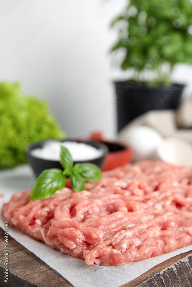 Raw chicken minced meat with basil on wooden board, closeup Raw chicken minced meat with basil on wooden board, closeup