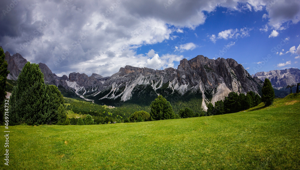 Dolomites, Italy, August 2017, alpine green meadow in the valley against the backdrop of mountains and blue sky