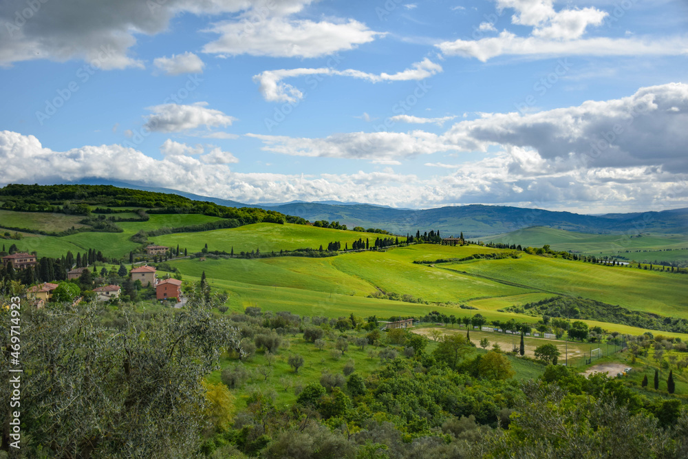 Tuscany, italy, may 2018, a view from a height of a green valley with roads lined with cypress trees and farm houses