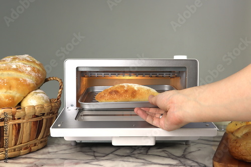 Fotografie, Tablou right hand of a lady housewife put the bread into white modern design toaster ov