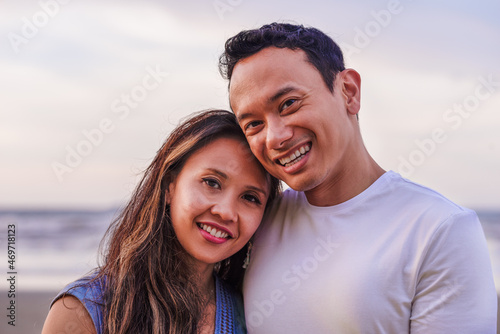 holidays, couple and family concept -portrait of young malaysian couple smiling outdoor on beach
