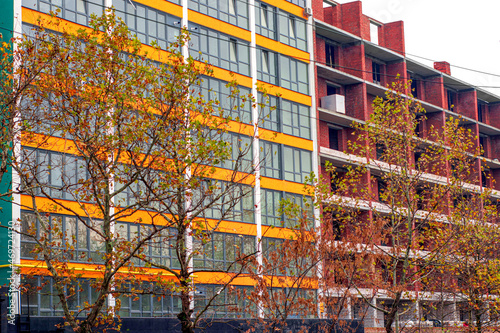 Construction of a red brick building on the background of a building with large panoramic windows