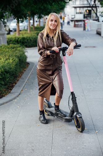 beautiful blonde woman in a cloak on an scooter