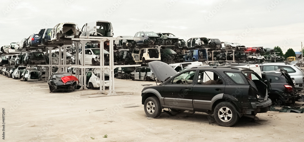 Old rusty corroded and crushed cars in car scrapyard. Car recycling. Ecological concept by dump of wrecked cars.