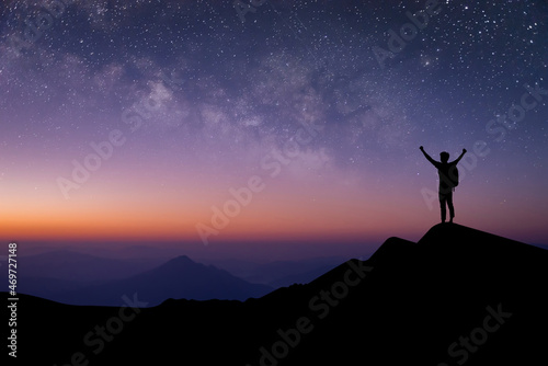 Silhouette of young traveler with backpack standing and watched the star and milky way alone on top of the mountain. He enjoyed traveling and was successful when he reached the summit.