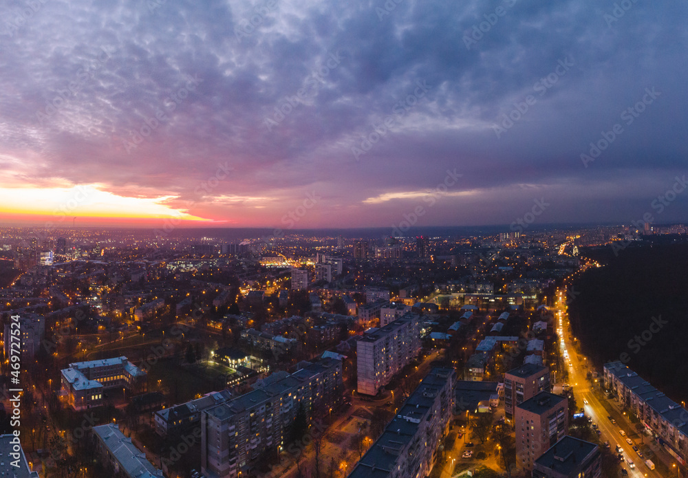 Aerial sunset scenic vibrant view on Kharkiv city, Pavlove pole. Night lights on streets of residential district and scenic cloudy purple sky after sunset. Cars driving moody illuminated streets
