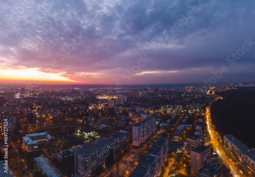 Aerial sunset scenic vibrant view on Kharkiv city, Pavlove pole. Night lights on streets of residential district and scenic cloudy purple sky after sunset. Cars driving moody illuminated streets