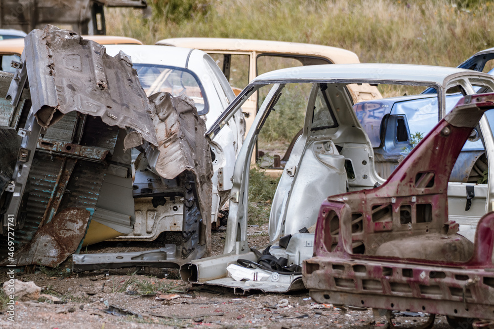 Metal broken cars body parts close-up in field. Car dump, wreck at a junkyard ready for recycling