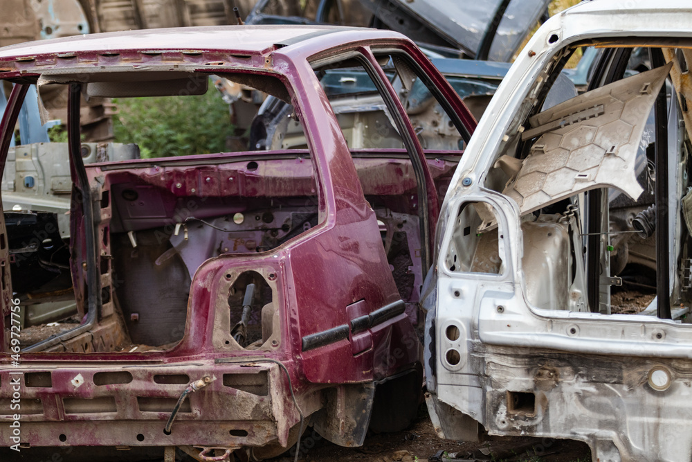 Fototapeta premium Two disassembled cars body parts outdoor close-up view. Car dump, wreck at a junkyard ready for recycling