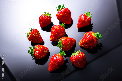 ripe red strawberries lie on a gradient black and white background