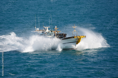 The fishing boat in sea splashes, floats with high speed.
