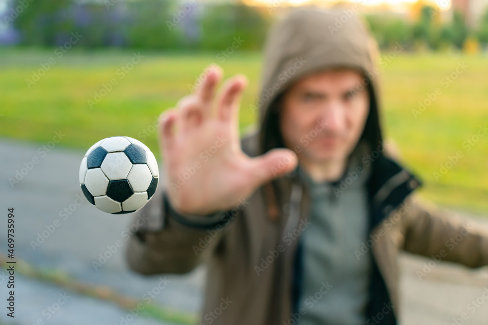 Naklejka premium The soccer ball flying in the air, the athlete catches with his hand. Man throws the ball with his hand