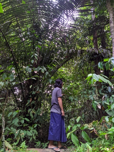 a man wearing a sarong is observing the thick forest in the Bogani Nani Wartabone national park, Gorontalo photo